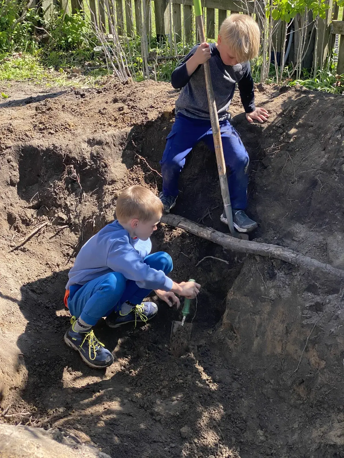 Two students digging with a shovel and hand auger