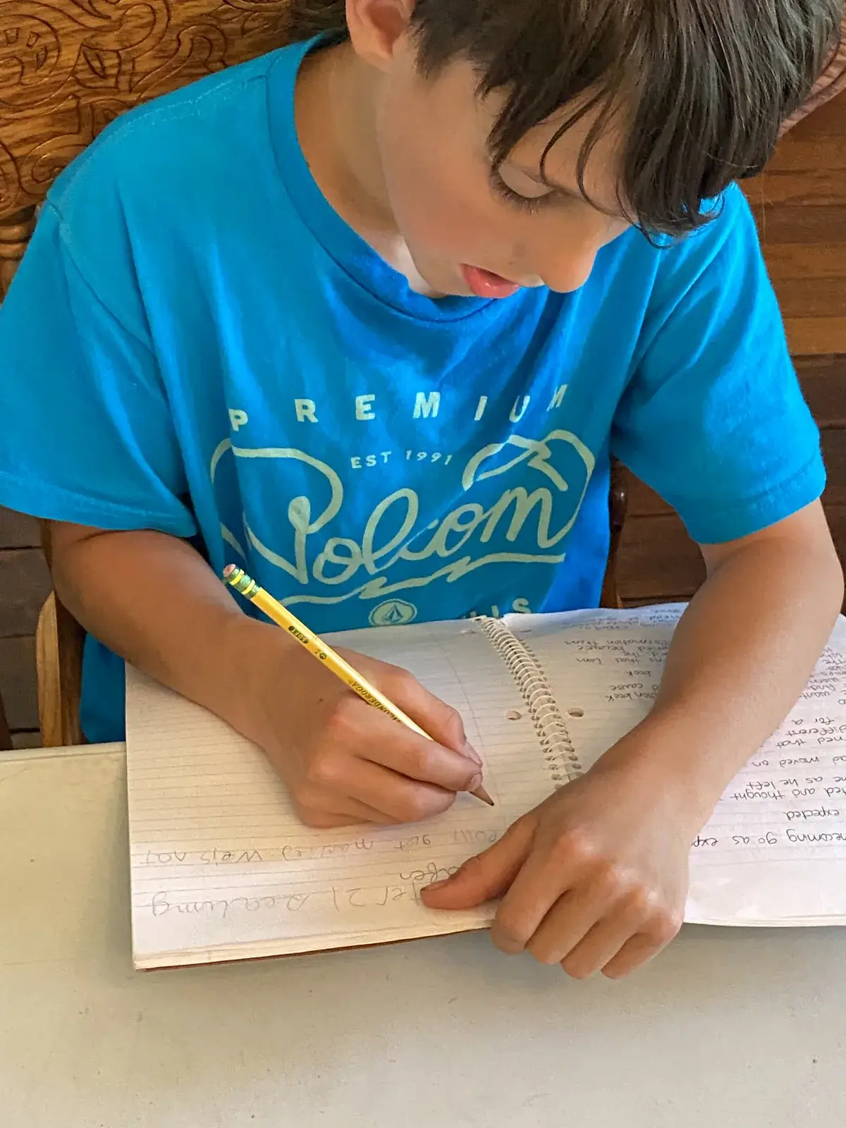 A WONDERfield student writing carefully in a spiral notebook