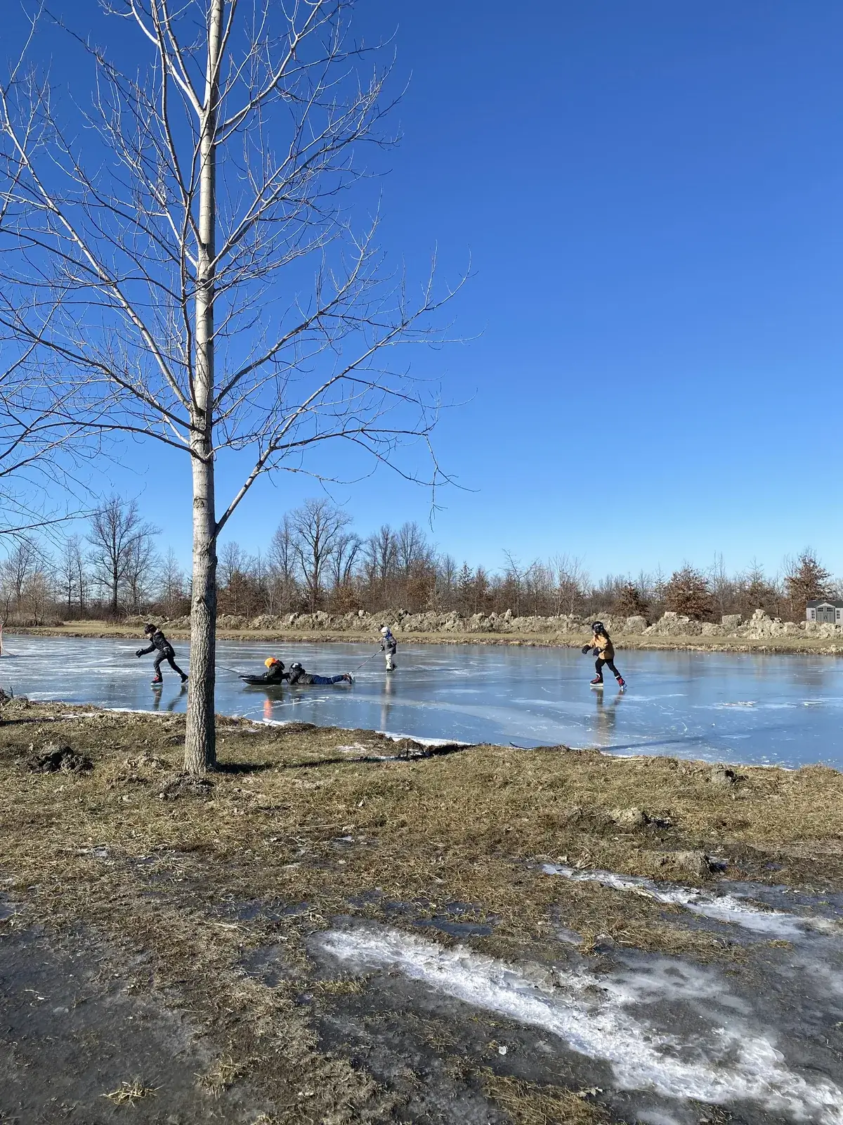 Students skating and playing hockey on a frozen pond on a winter afternoon